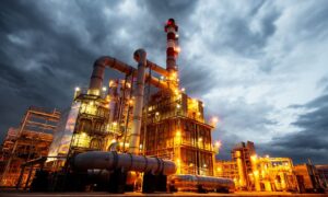 yellow-lit pipes against cloudy sky in refinery construction