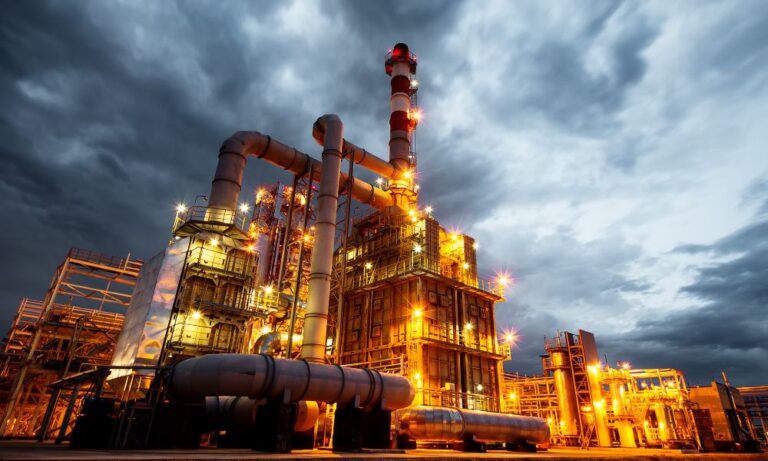 yellow-lit pipes against cloudy sky in refinery construction